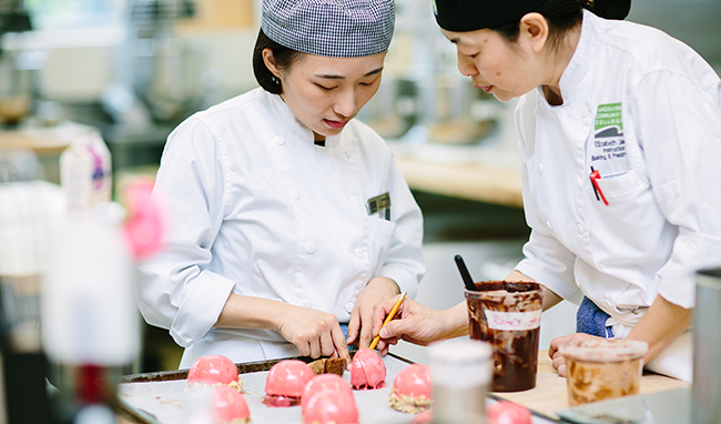 A ֦Ƶ baking instructor and student look over pink pastries